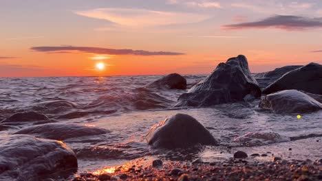 Meereswellen-Rollen-Auf-Die-Felsen,-Sommersonnenuntergang-Im-Hintergrund