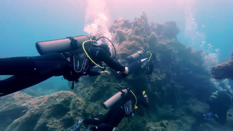 Scuba-Divers-with-snorkel-gear-and-oxygen-tank-explore-underwater-sea,-Greece