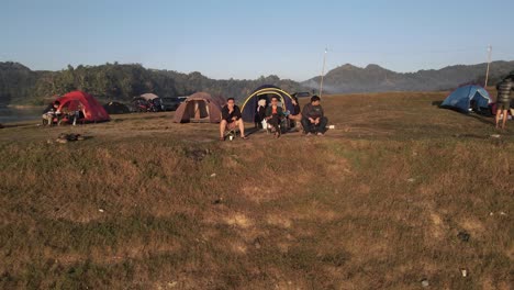 An-aerial-view-shows-several-people-camping-relaxing-and-cooking,-in-a-plain-area-near-the-Sermo-Reservoir,-Yogyakarta,-Indonesia