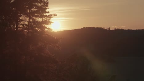 El-Sol-Se-Pone-Sobre-Un-Paisaje-Montañoso-Y-Boscoso,-Proyectando-Una-Luz-Suave-Y-Dorada-Sobre-La-Escena.