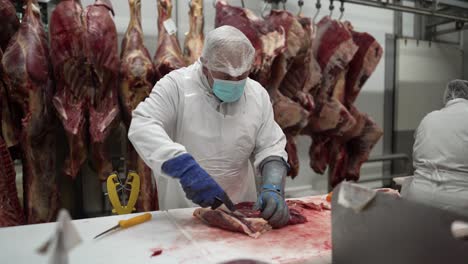 Beef-meats-being-trimmed-of-fat-by-workers-at-a-meat-processing-plant-table,-Medium-shot