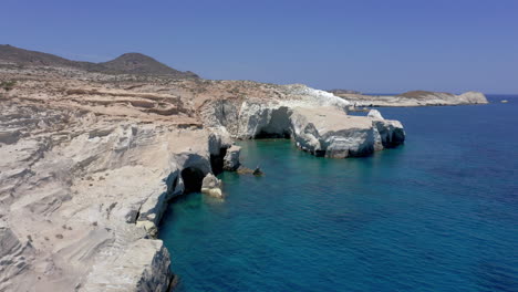 Aeriall:-Slow-panoramic-drone-shot-of-white-cliffs-and-caves-on-the-coast-of-Sarakiniko-beach-in-Milos-Island