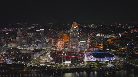 Vuelo-Aéreo-V46-Sobre-El-Río-En-Cincinnati,-Ohio,-Que-Captura-Un-Deslumbrante-Espectáculo-De-Fuegos-Artificiales-En-El-Cielo-Nocturno-Contra-El-Paisaje-Urbano-Del-Centro-De-La-Ciudad,-El-Estadio-De-Béisbol-Y-La-Arena-Junto-Al-Río;-Filmado-Con-Inspire-3-8k---Septiembre-De-2023