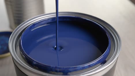 Mixing-blue-paint-with-a-wooden-stick-on-a-wooden-table