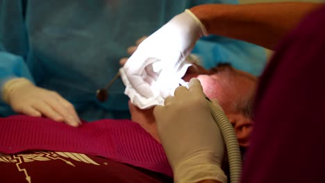 Patient-receiving-dental-treatment-from-a-dentist-and-assistant-in-a-clinic