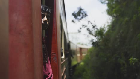 A-shy-kid-hangs-out-of-a-moving-train-in-lush-Sri-Lankan-countryside