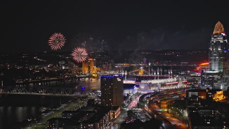 Cincinnati-Ohio-Aerial-v47-flyover-capturing-waterfront-sport-complexes,-illuminated-downtown-cityscape-with-fireworks-display-on-the-night-sky-over-the-river---Shot-with-Inspire-3-8k---September-2023