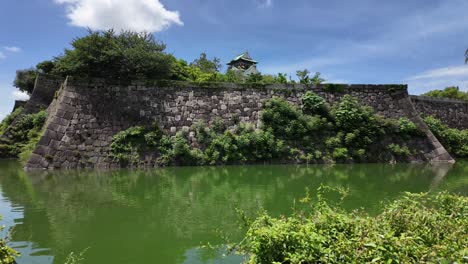 Scene-of-an-Edo-period-style-boat-navigating-the-waters-of-the-castle-moat-at-Osaka-Castle,-Japan