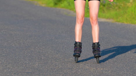 Close-up-of-a-person-rollerblading-on-a-paved-road,-wearing-black-inline-skates