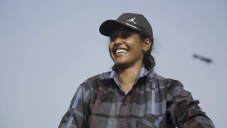 Smiling-fisherwoman-in-plaid-shirt-and-cap-under-clear-sky