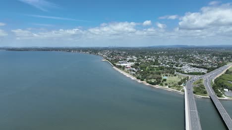 Drone-establishing-shot-of-Ted-Smout-Memorial-Bridge,-camera-pull-away-shot-with-Bridge,-Moreton-Bay,-Ocean-and-Brisbane-City-in-background