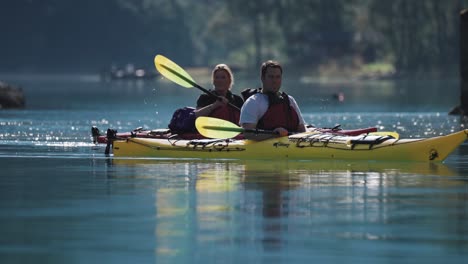 A-couple-of-kayakers-paddling,-swaying-on-the-waves-in-the-Naeroy-fjord