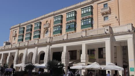 Una-Toma-Panorámica-Del-Edificio-De-La-Casa-Rocca-Piccola-En-La-Valeta,-Malta,-Con-Turistas-Y-Residentes-Visitando-El-Famoso-Café-Royal.