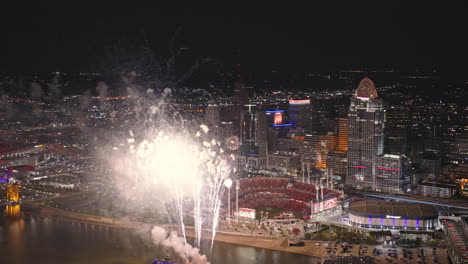 Cincinnati-Ohio-Aerial-v52-flyover-capturing-close-ups-of-river-fireworks,-illuminating-the-night-sky-against-downtown-cityscape-and-Great-American-Ball-Park---Shot-with-Inspire-3-8k---September-2023