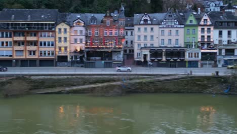 Aerial-parallel-drone-view-panning-to-the-right-of-the-city-of-Cochem,-Rhineland-Palatinate,-Germany-with-colorful-houses,-street-and-cars