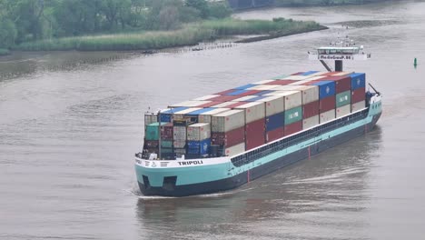 General-cargo-ship-Tripoli,-navigating-along-Oude-Maas-river,-aerial