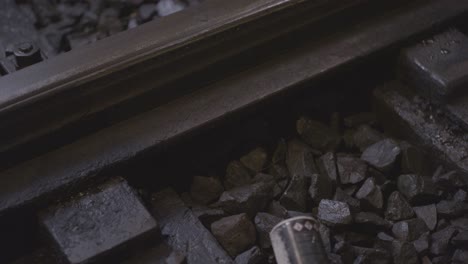 Spray-can-falling-on-railroad-tracks-as-a-train-passes,-evoking-urban-decay