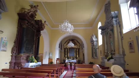 A-pan-across-a-small-historic-Christian-church-in-Cavtat-Croatia-attended-by-a-middle-aged-couple