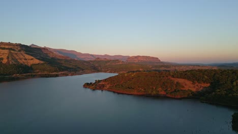 Vista-Aérea-De-La-Presa-De-Ghatghar-Y-Kokan-Kada-En-Un-Día-Soleado-En-Bhandardhara,-Rodeada-De-Algunas-Colinas-Increíbles-Y-Un-Cielo-Azul,-Maharashtra,-India,-Dron