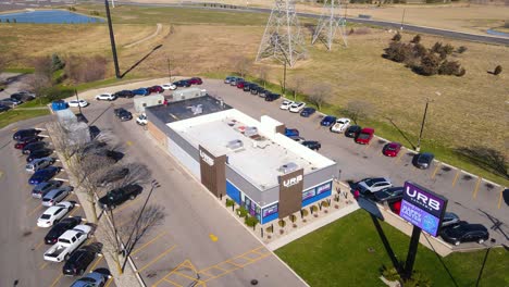 Vista-Aérea-Con-Dron-Del-Edificio-De-La-Tienda-De-Cannabis-De-La-Ciudad-Y-El-Estacionamiento