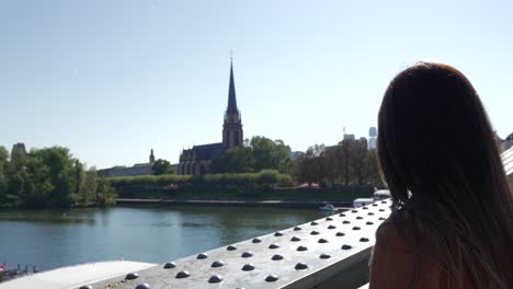 Young-female-woman-tourist-in-Frankfurt-Germany-looking-at-Main-river-landmark