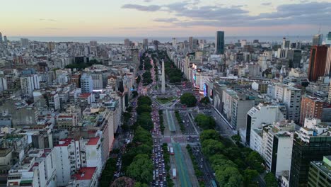 Aerial-view-with-Drone-daylight-of-9-de-Julio-Avenue-and-obelisk-with-the-colors-of-the-sunset-and-the-buildings-of-the-city-of-Downtown,-Buenos-Aires,-Argentina