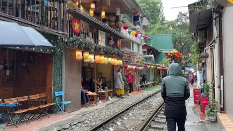 Calle-Del-Tren-De-Hanoi,-Vietnam.-Personas-Con-Paraguas-Caminando-Por-Las-Vías