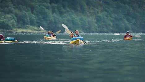 Un-Grupo-De-Kayakistas-Rema-A-Través-Del-Fiordo-De-Naeroy,-Sus-Botes-Se-Balancean-Con-Las-Olas.