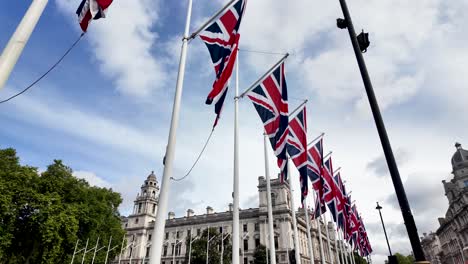 Row-of-union-jack-flags-waving-in-the-wind-with-a-london-building-in-the-background