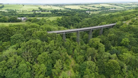 Vista-Aérea-De-Turistas-Cruzando-El-Viaducto-De-Meldon-Disfrutando-Del-Paisaje-Escénico-De-Devon,-Inglaterra