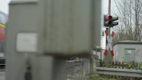 Blurry-railroad-crossing-equipment-with-sharp-focus-on-a-red-signal-light,-capturing-a-quiet,-overcast-day