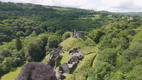 Drone-orbital-fly-in-capturing-Okehampton-Castle-amidst-dense-greenery-in-Devon,-UK