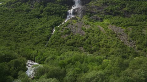 Majestic-waterfall-cascades-down-lush-green-mountainside-in-Norway's-scenic-landscape