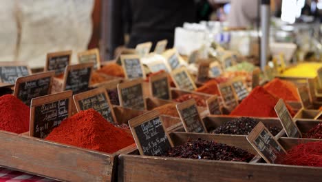 Colorful-spice-display-at-Le-Marché-Provençal-in-Antibes,-France-with-labels-and-vibrant-hues