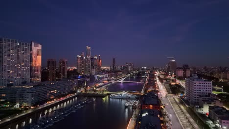 Aerial-drone-view-from-Puerto-Madero-at-night-with-a-view-of-the-buildings-and-docks-in-the-city-of-Buenos-Aires,-Argentina