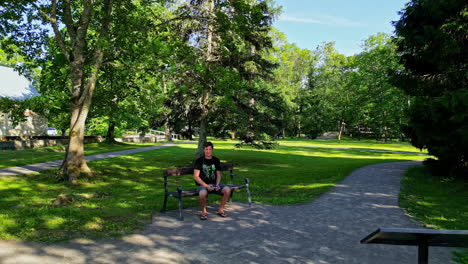 A-man-flying-drone-sitting-on-a-bench-near-Keila-waterfall-during-daytime-in-Estonia