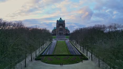 Aerial-drone-view-in-descent-the-basilica-of-the-sacred-heart-in-Brussels,-Belgium-on-a-beautiful-sunset-cloudy-sky