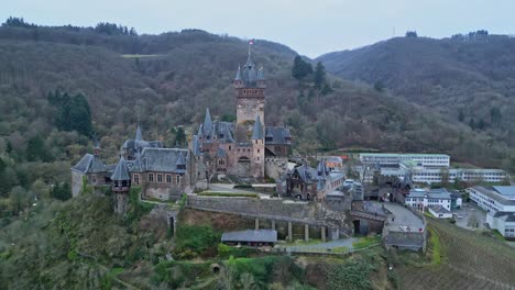 Aerial-zoom-in-drone-view-of-Reichsburg-Cochem-Castle,-Rhineland-Palatinate,-Germany-on-a-beautiful-cloudy-sky