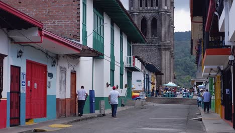 View-of-Jardin-Basilica-from-narrow-side-street,-tourists-in-plaza