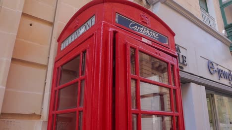 Una-Toma-Detallada-Inclinada-Hacia-Abajo-De-Una-Cabina-Telefónica-Roja,-Que-Muestra-La-Arquitectura-única-De-La-Cabina-Y-Sus-Colores-Vivos.