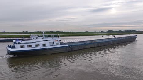 The-Primair-Cargo-Ship-is-Cruising-the-River-in-Alblasserdam,-South-Holland,-Netherlands---Tracking-Shot