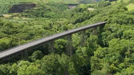 Aerial-fly-in-of-Meldon-Viaduct-and-Okement-Valley,-highlighting-the-bridge-and-surrounding-landscape