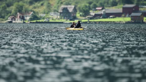 Two-kayakers-enjoy-a-day-on-the-Naeroy-fjord,-paddling-and-swaying-on-the-waves