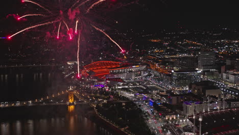 Cincinnati-Ohio-Aerial-v49-flyover-river-capturing-close-up-views-of-brilliant-fireworks-displaying-on-the-night-sky-against-illuminated-downtown-cityscape---Shot-with-Inspire-3-8k---September-2023