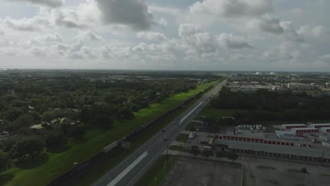 An-aerial-drone-view-of-a-freight-train-heading-south,-passing-through-Clear-Lake,-Webster,-and-League-City-towards-Galveston,-Texas