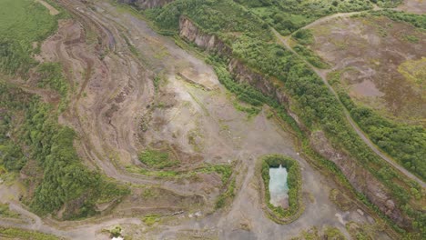 Aerial-rising-view-of-a-disused-abandoned-quarry-now-returning-to-nature-illuminated-by-sunlight