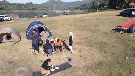 An-aerial-view-shows-several-people-camping-relaxing-and-cooking,-in-a-plain-area-near-the-Sermo-Reservoir,-Yogyakarta,-Indonesia