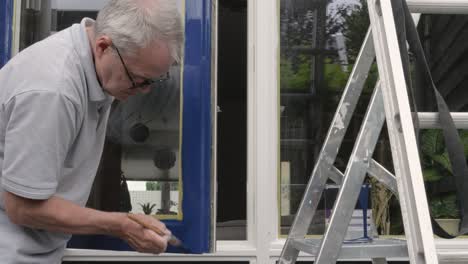 Un-Hombre-Mayor-Pintando-Los-Marcos-De-Las-Ventanas.