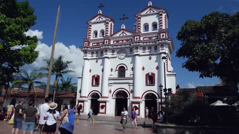 Tourists-appreciate-bright-white-Catholic-church-in-Guatape,-Colombia