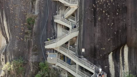 Tourists-start-climbing-staircase-up-Penol-Stone,-huge-granite-outcrop